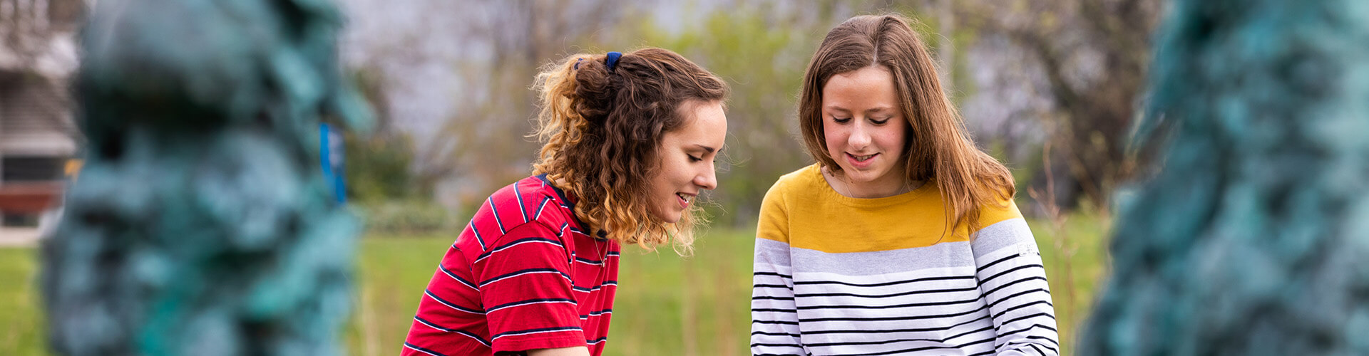 Students looking at laptop next to lake